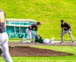 Baseball players in action during a game, with one player sliding into base while teammates prepare to make a play.