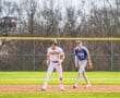 Two high school baseball players on the field, one on second base, in a sunny spring game.