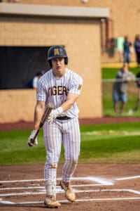 Baseball player in striped uniform prepares to bat on the field, showcasing focus and athleticism during the game.