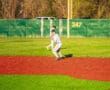 Young baseball player in a uniform fielding on a bright, vibrant turf in a sunny park setting.