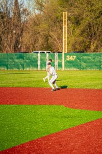 Young baseball player in a uniform fielding on a bright, vibrant turf in a sunny park setting.