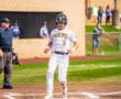 Baseball player in pinstripes crossing home plate, umpire in the background, vibrant field setting.