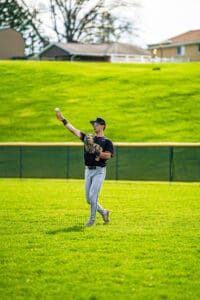 Player in baseball gear catches a ball on the field, showcasing athleticism and focus during a game.