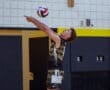Young male volleyball player preparing to serve, focusing on the ball in a gym setting. Dynamic sports action shot.