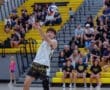 A volleyball player sets the ball during a match, with a cheering crowd in the background.