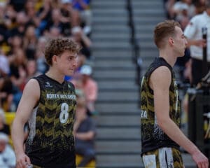 North Allegheny volleyball players on the court, focused during a competitive match with cheering fans in the background.