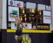 Volleyball player serving during a match, score: Tigers 18, Visitor 4, with 1 minute left in the period.