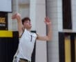 Teenage volleyball player serves the ball in a gym, showcasing focus and athleticism in a dynamic moment.