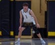 Young male basketball player in action stance, wearing a team jersey and shorts on the court during a game.