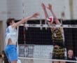 High school volleyball players compete at the net, one spiking and the other attempting a block during a match.