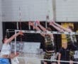 Volleyball players jumping to block a spike at a competitive match, showcasing athletic skill and teamwork.