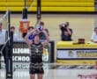 A North Allegheny volleyball player sets the ball as spectators and announcers watch during a high school match.
