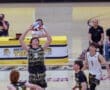 Player prepares to set a volleyball during a high school match, with teammates and coaches in the background.