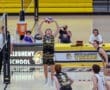 High school volleyball match with a player setting the ball, while teammates and spectators watch intently.
