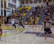 High school boys' volleyball match in gym; players in action with engaged crowd in the stands.