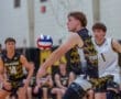 High school volleyball match action, player prepares to set the ball with teammates in the background, captured indoors.