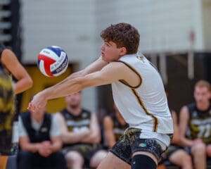 High school athlete prepares to pass a volleyball during a competitive match, showcasing skills and teamwork.