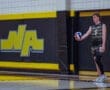 High school volleyball player in action, ready to serve with a ball in hand against a bold yellow and black background.