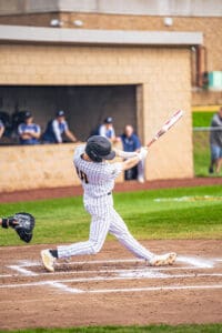Baseball player in striped jersey swings bat during a game, capturing the excitement of a dynamic moment on the field.