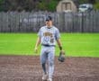 A baseball player in a gray Tigers uniform walks across the field, preparing for the game on a sunny day.