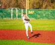 Player fields a ground ball on a colorful baseball diamond, preparing to make a throw during practice on a sunny day.