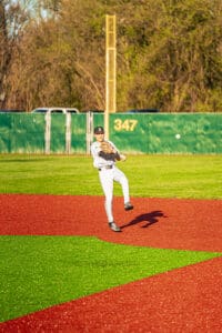 Player fields a ground ball on a colorful baseball diamond, preparing to make a throw during practice on a sunny day.