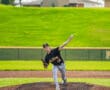 Young baseball pitcher in action on the mound, wearing a team uniform and preparing to throw a pitch.