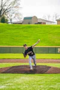 Young baseball pitcher in action on the mound, wearing a team uniform and preparing to throw a pitch.