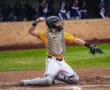 Baseball catcher in action, throwing a ball from home plate while wearing a protective gear and focused expression.