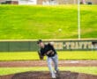 High school baseball pitcher in action, delivering a pitch on a sunny day at the field.
