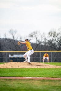 Baseball pitcher prepares to pitch from the mound during a game, with teammates in the background.
