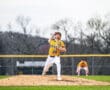 Young baseball pitcher in action on the mound, wearing a yellow jersey and showcasing throwing form during a game.