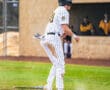 Baseball player in a striped uniform celebrates on the field, showcasing athleticism after a successful play.