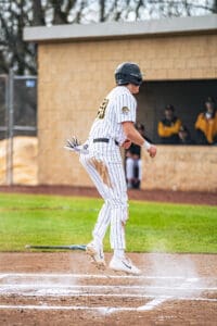 Baseball player in a striped uniform celebrates on the field, showcasing athleticism after a successful play.