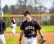 Baseball player in Tigers uniform walking on the field during practice on a sunny day. Teamwork and preparation atmosphere.