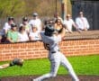 Youth baseball player in action, swinging a bat during a game with spectators in the background. Perfect spring day.