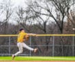 Youth baseball player in yellow jersey fields and throws a ball during a game on a grassy field.