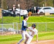 Baseball players compete at third base, one sliding in while the other prepares to catch a throw in a lively game.