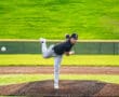 Young baseball pitcher in mid-throw on a field, showcasing athleticism and focus on the pitcher's mound.