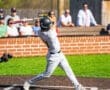 A young baseball player swings a bat during a game, with spectators watching in the background on a sunny day.