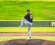 Young baseball pitcher on the mound, wearing number 37, preparing to throw under a sunny sky.