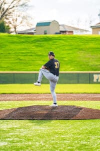 Young baseball pitcher on the mound, wearing number 37, preparing to throw under a sunny sky.