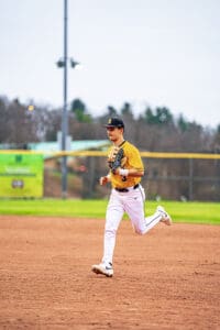 A baseball player in a yellow jersey sprinting on the field with a glove in hand during a game.