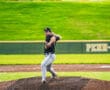 Baseball pitcher in action on the mound, focused and ready to throw during a game on a sunny day.