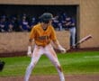 A young baseball player in a yellow jersey prepares to bat, showcasing a focused stance on the field.