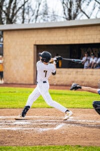 Young baseball player in striped uniform swings bat during a game, capturing dynamic athletic energy on the field.