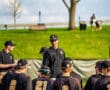 Baseball coach discussing strategies with players during practice on a sunny day at the field. Team in black uniforms.
