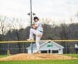 Baseball pitcher in action, raising his knee on the mound, ready to deliver a pitch on a sunny day.