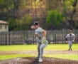 Young pitcher on the mound prepares to throw a baseball in a vibrant green field during a sunny game day.