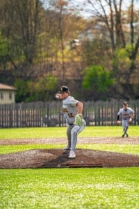 Young pitcher on the mound prepares to throw a baseball in a vibrant green field during a sunny game day.